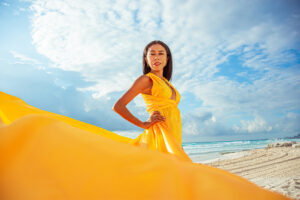señorita con vestido volador amarillo en la playa de cancun